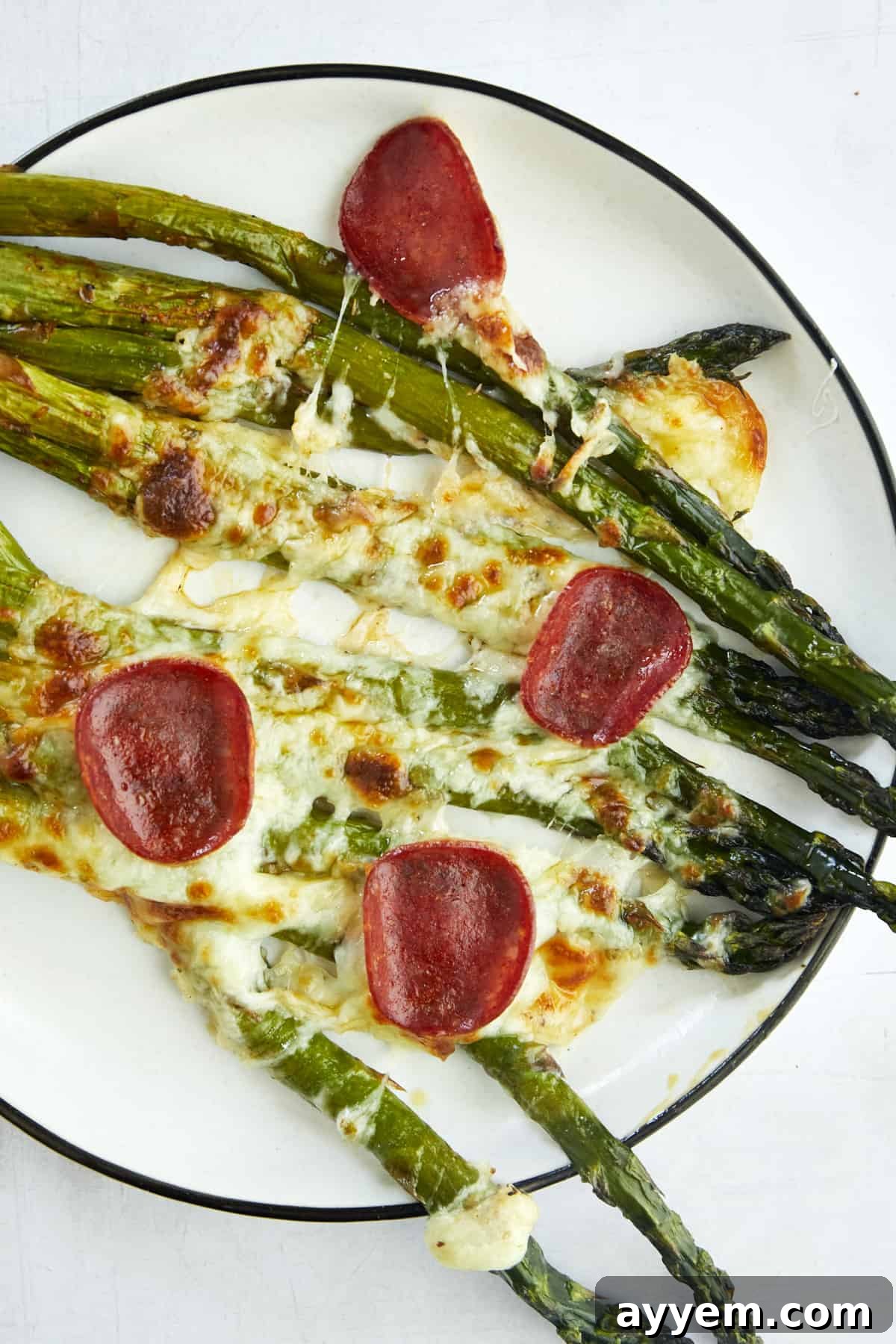 A serving of pizza-flavored oven baked asparagus on a plate. 