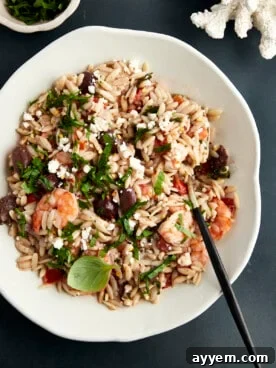 A bowl of savory Shrimp Orzo Bake topped with fresh herbs, ideal for a quick dinner.