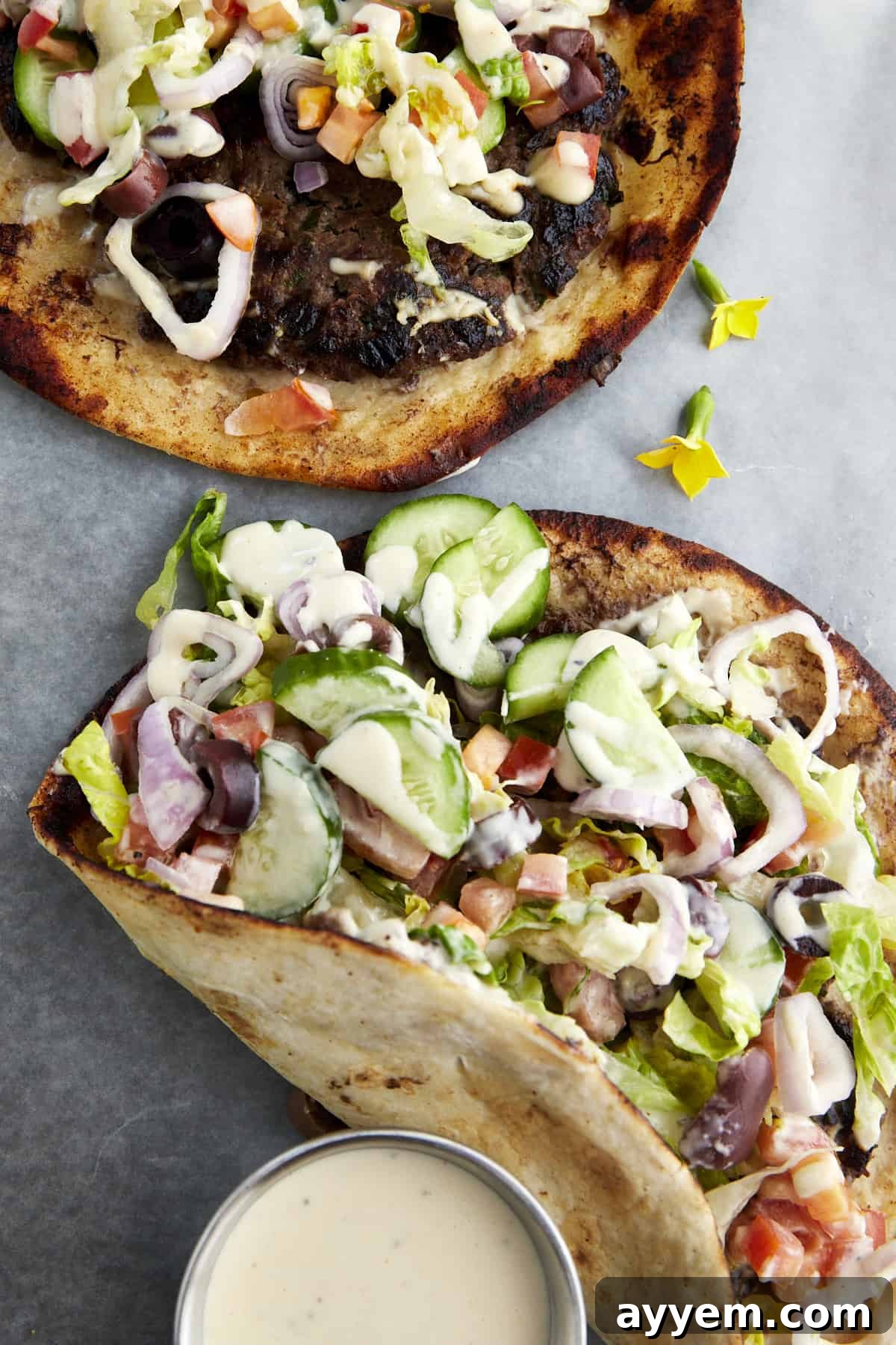 Two Greek-inspired smashed tacos with a side of tahini. 