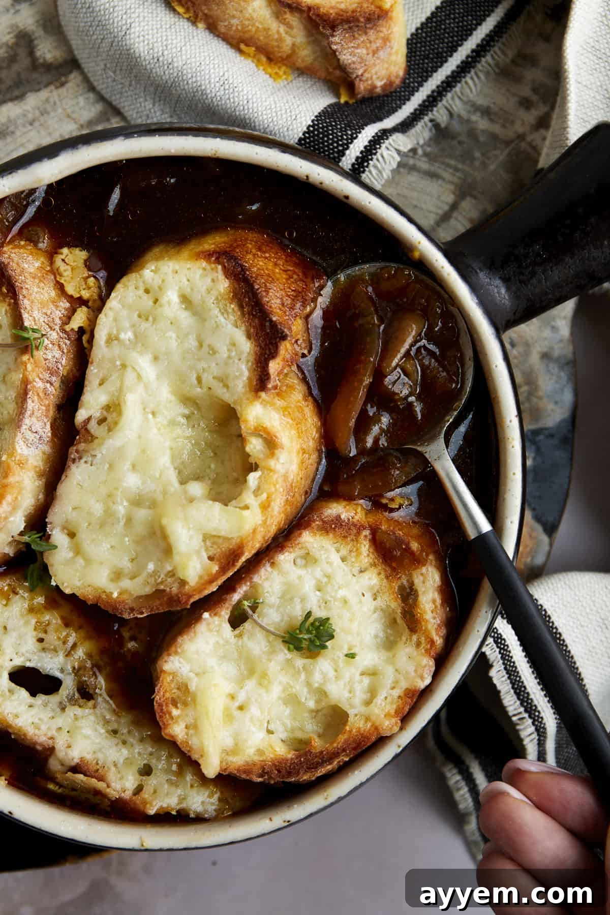 A spoon scooping up a bite of easy French onion soup, showcasing the melted cheese and tender onions.