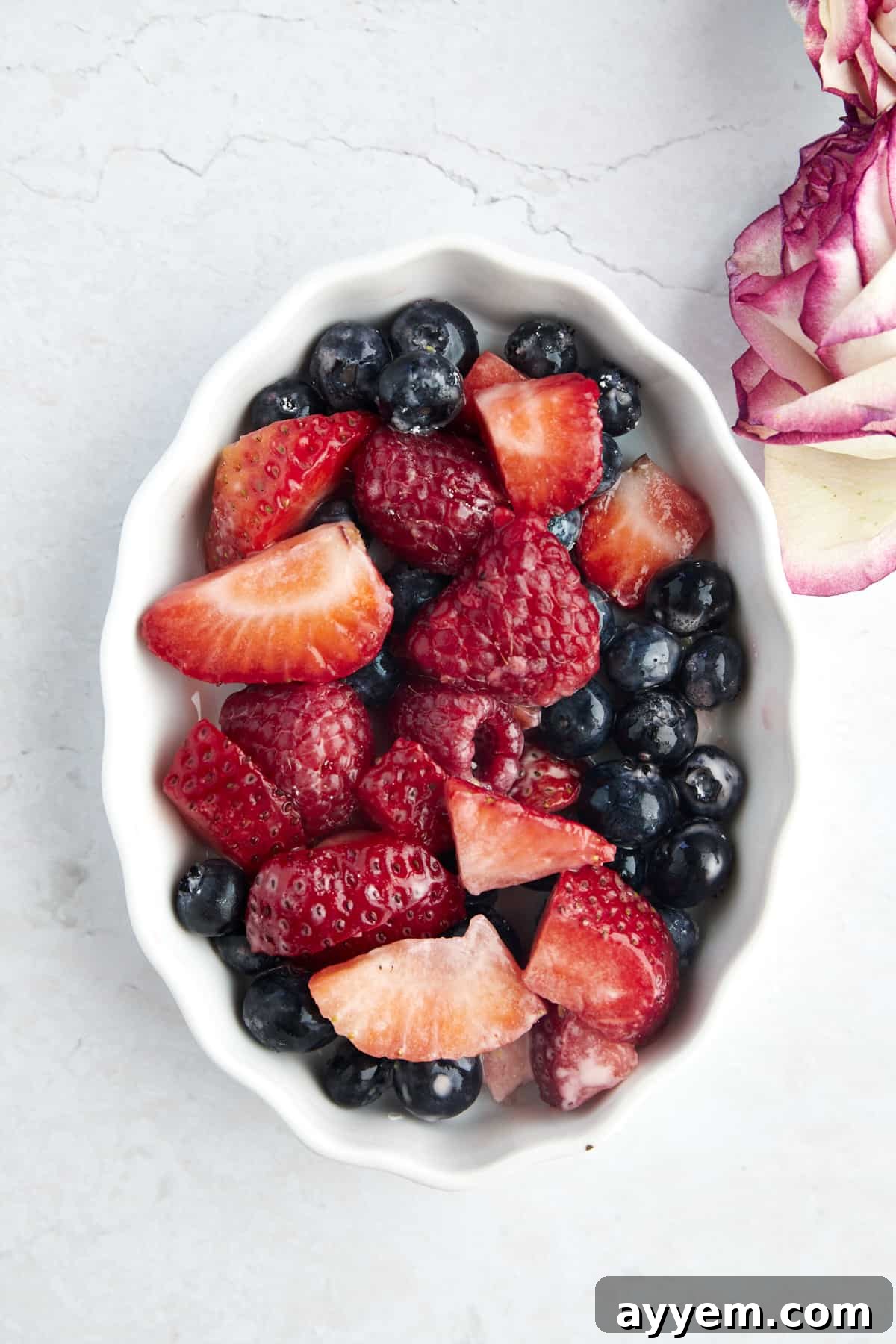 Raspberries, strawberries, and blueberries in an oval baking dish, ready for baking. A colorful display of fresh fruit.