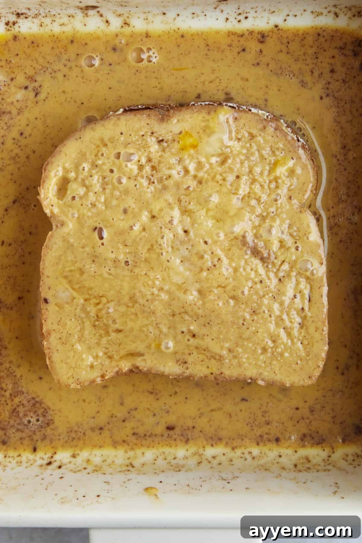 Cream cheese stuffed bread being dipped in an egg wash. 