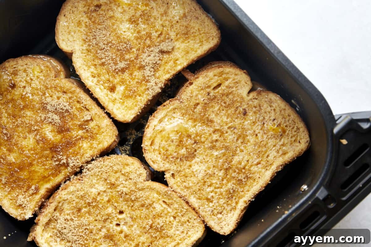 Four uncooked cream cheese stuffed french toast sandwiches in an air fryer basket. 