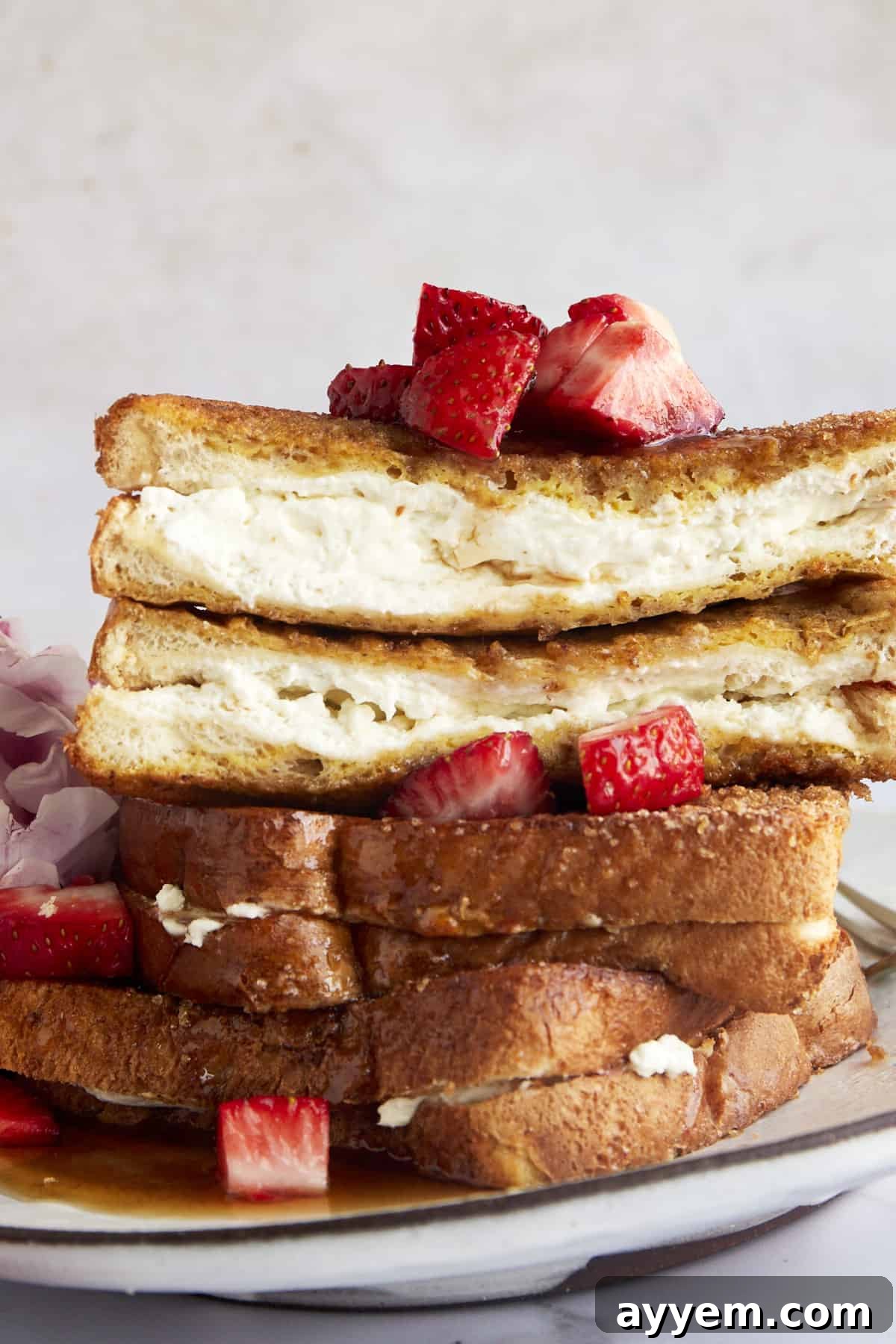 Stacked air fryer french toast with the top piece sliced in half showing the cream cheese center. 