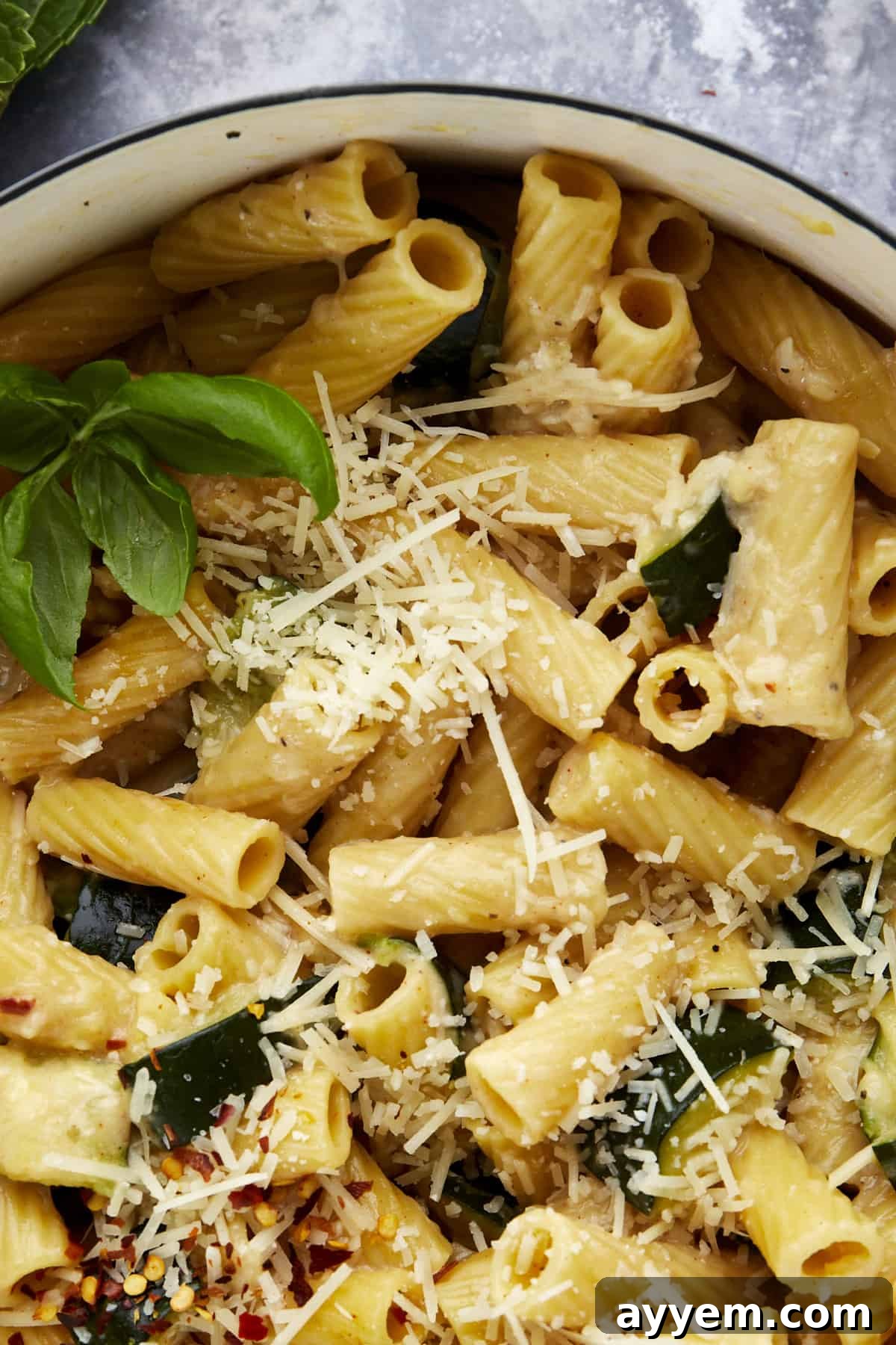 Close up image of cooked pasta with zucchini topped with Parmesan cheese.