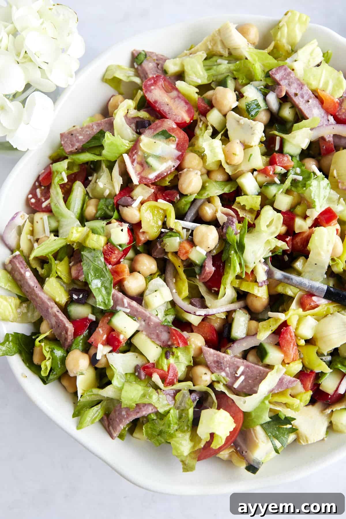 A fork piercing through a delightful mix of dressed Italian chopped salad, ready to be enjoyed.