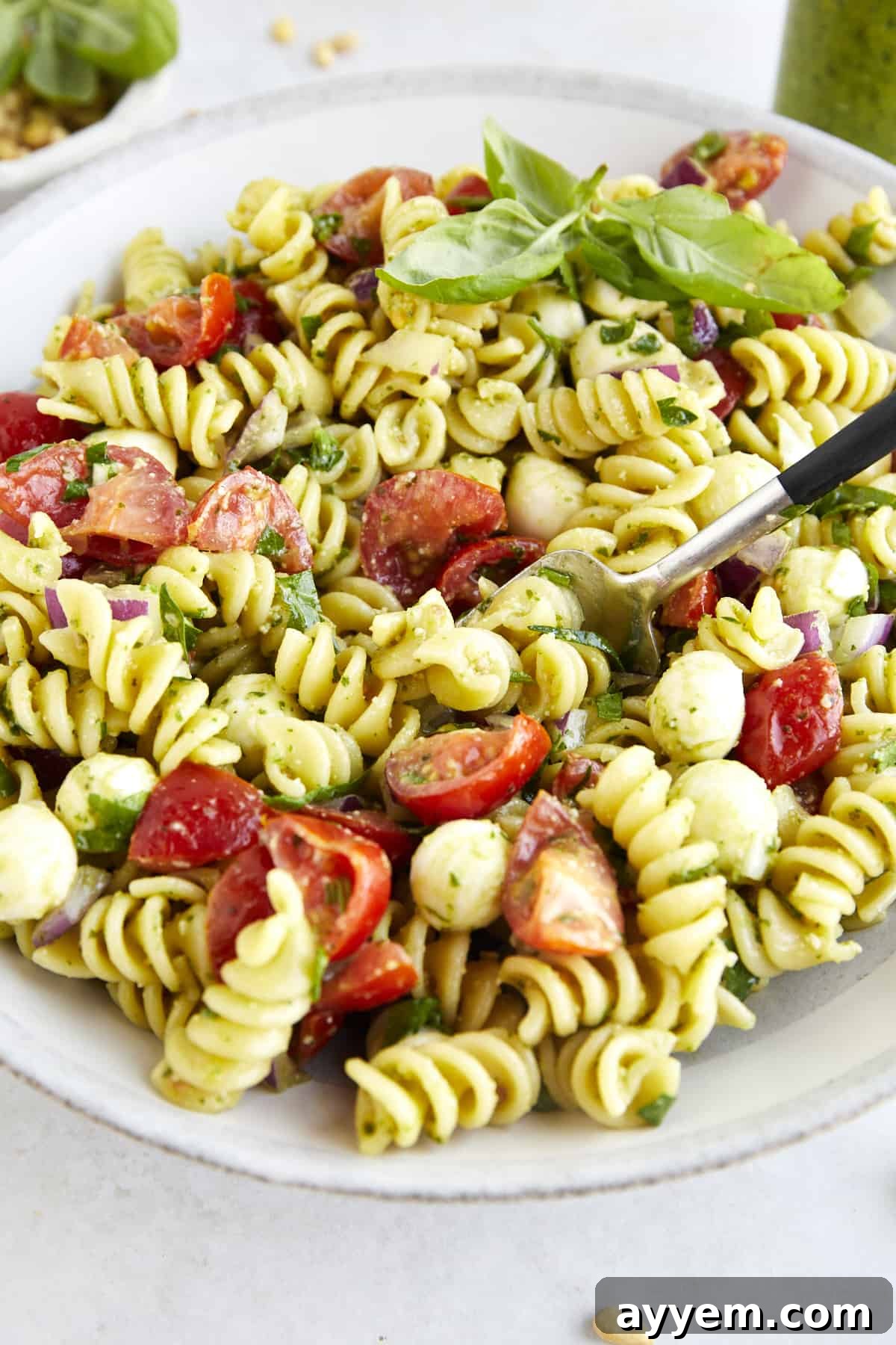 A fork spearing a bite of pasta salad with pesto. 