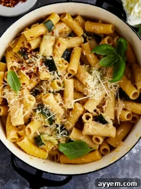 Overhead image of a pot of pasta with zucchini, vibrant green and creamy, garnished with red pepper flakes