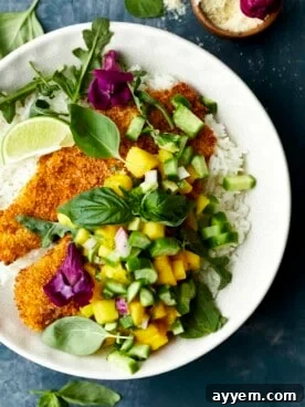 A bowl of fragrant coconut rice with perfectly air-fried tilapia and fresh, colorful mango salsa