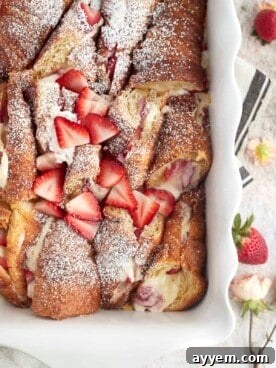 Strawberry Mascarpone French Toast in a baking dish, generously garnished with fresh strawberries and powdered sugar