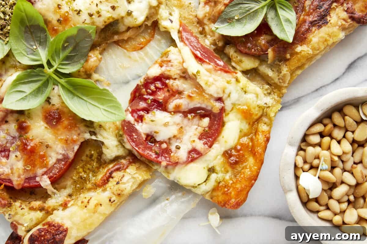 Multiple slices of a freshly baked Tomato Pesto Puff Pastry, showcasing its flaky crust, melted cheese, and vibrant toppings.
