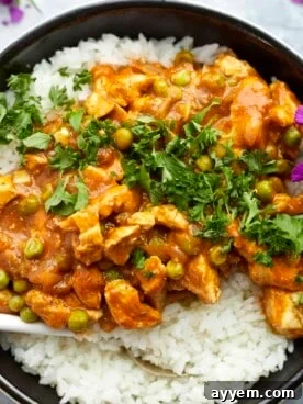 Overhead view of rich Madras Curry Chicken simmering in a pan, garnished with fresh cilantro.