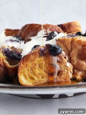 Golden Croissant Blueberry French Toast Bake generously drizzled with maple syrup.