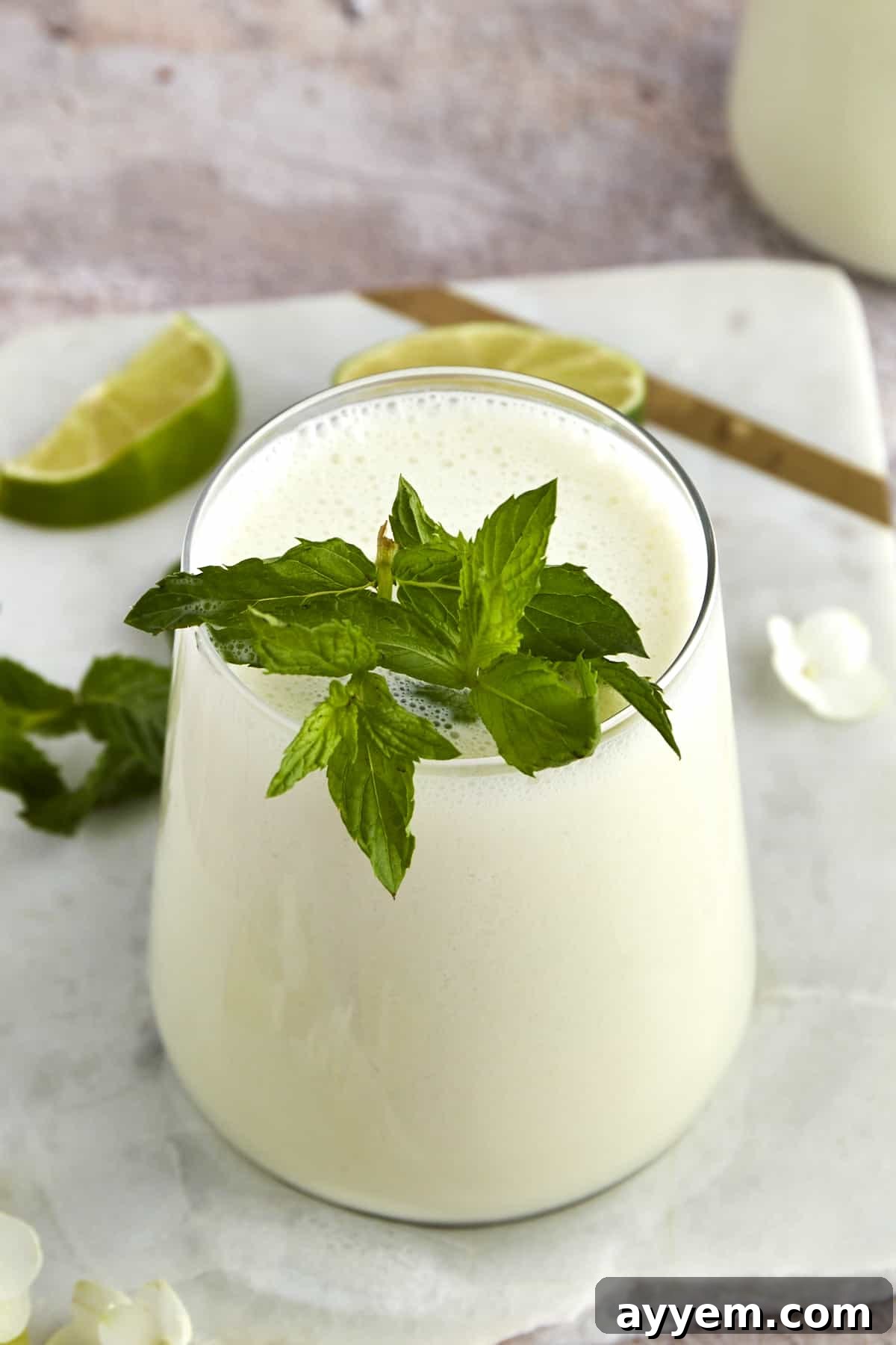 A glass of creamy Limonana with mint leaves and a lime slice on the rim, showcasing its smooth texture.