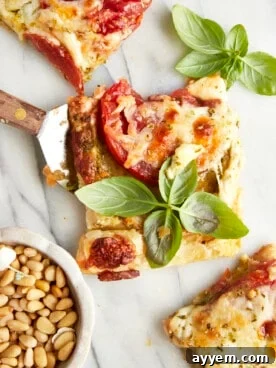 A golden-brown slice of savory tomato pesto puff pastry topped with vibrant fresh basil, ideal for a quick appetizer or light lunch.