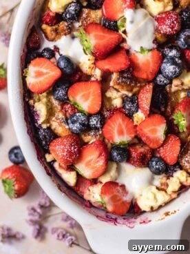 A beautiful Berry Brioche Cream Cheese French Toast Bake, generously topped with fresh berries and a dusting of powdered sugar, perfect for a decadent breakfast or brunch.