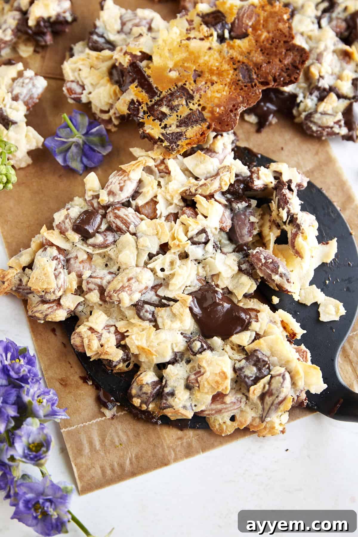 A perfectly broken chunk of coconut chocolate almond bark, highlighting the golden toasted coconut and visible almond pieces.