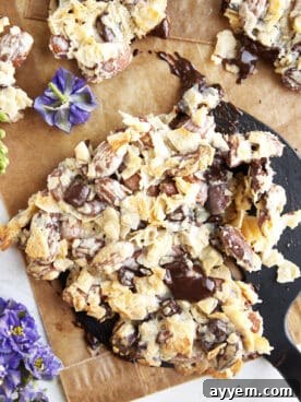 A spatula lifting a generous piece of homemade coconut chocolate almond bark, revealing its luscious layers of coconut, chocolate, and almonds.