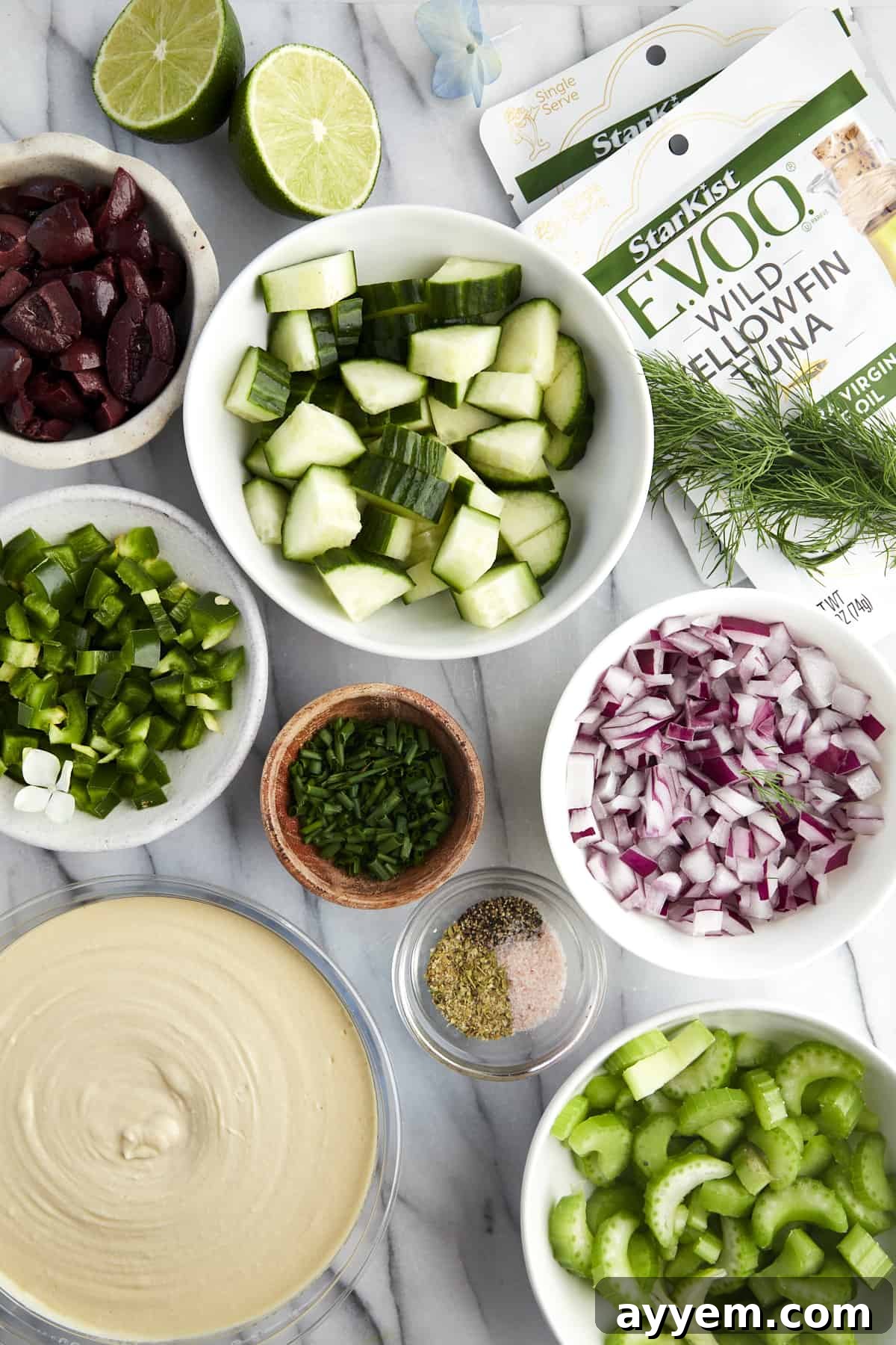 Ingredients needed for Mediterranean tuna salad arranged aesthetically on a wooden board.