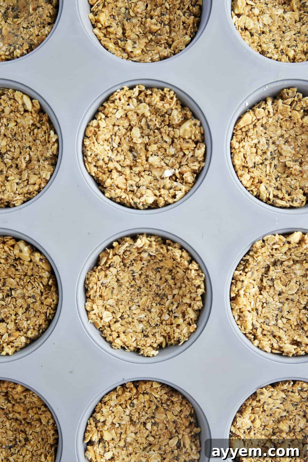The oat mixture pressed into a muffin pan, forming the base of the no-bake cups.