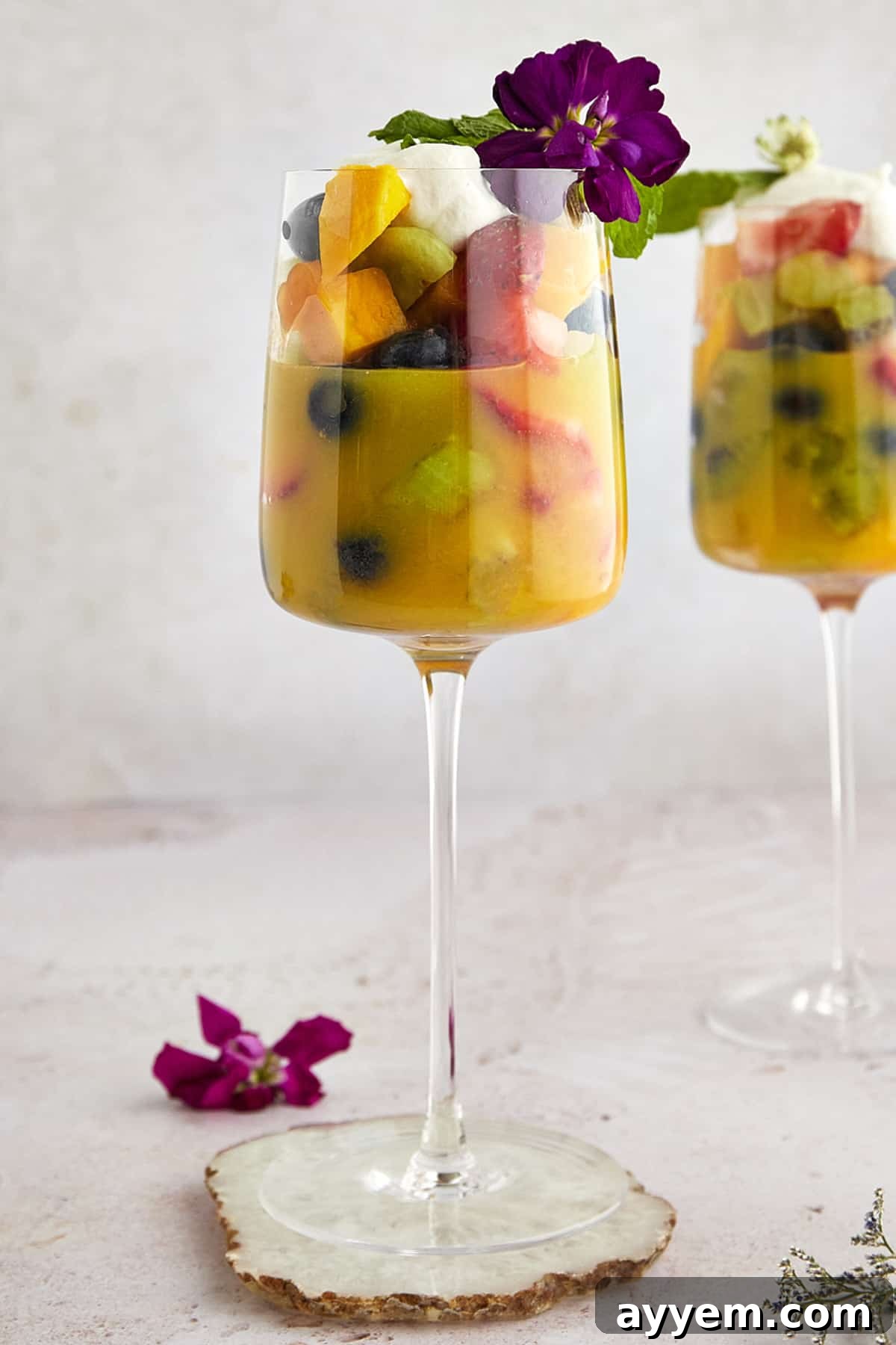 A tall glass filled with Fakhfakhina, an Egyptian fruit salad drink, featuring a colorful array of diced fruits and sweet juice.