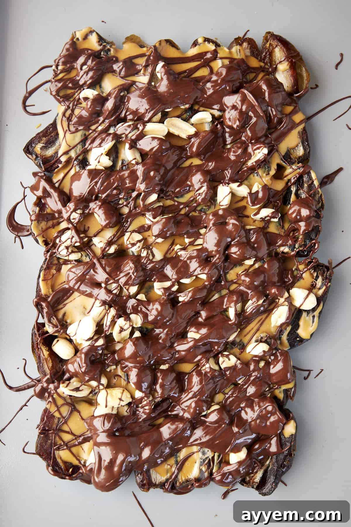 The Viral Date Bark Sensation 4 Dates topped with peanut butter, peanuts, and melted chocolate.