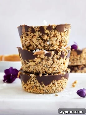 Three no bake peanut butter oat cups stacked on top of each other, garnished with sea salt flakes.