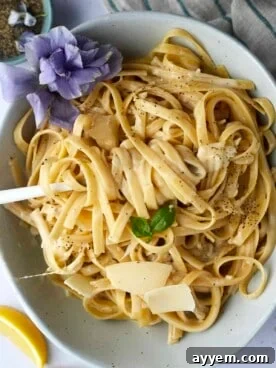 A beautifully plated bowl of One Pot Fettuccine Alfredo with a fork twirled around a perfect bite.