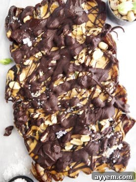 A large slab of Snickers-inspired Date Bark, beautifully topped with flaky sea salt and chopped nuts.