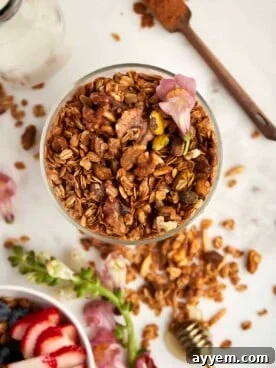 Overhead image of a clear jar filled with homemade Baklava Granola, featuring nuts and oats.