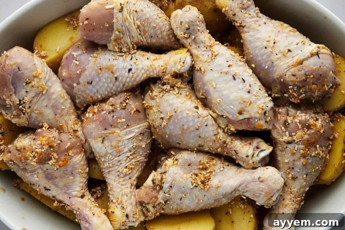 Raw chicken drumsticks and halved Yukon Gold potatoes in a baking dish, coated in a rich garlic parmesan marinade.