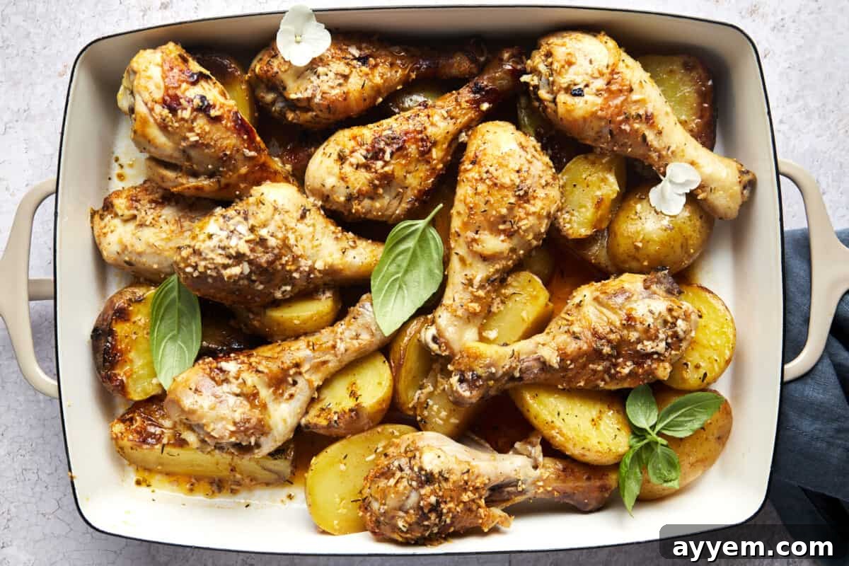 Freshly baked garlic parmesan chicken drumsticks and potatoes in a casserole dish, glistening and ready to eat.