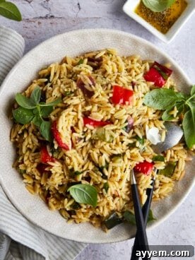 A vibrant bowl of roasted veggie pasta salad with orzo, featuring colorful vegetables.