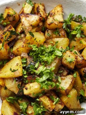A plate of crispy air fryer golden potatoes drizzled with spicy harissa sauce and fresh parsley.