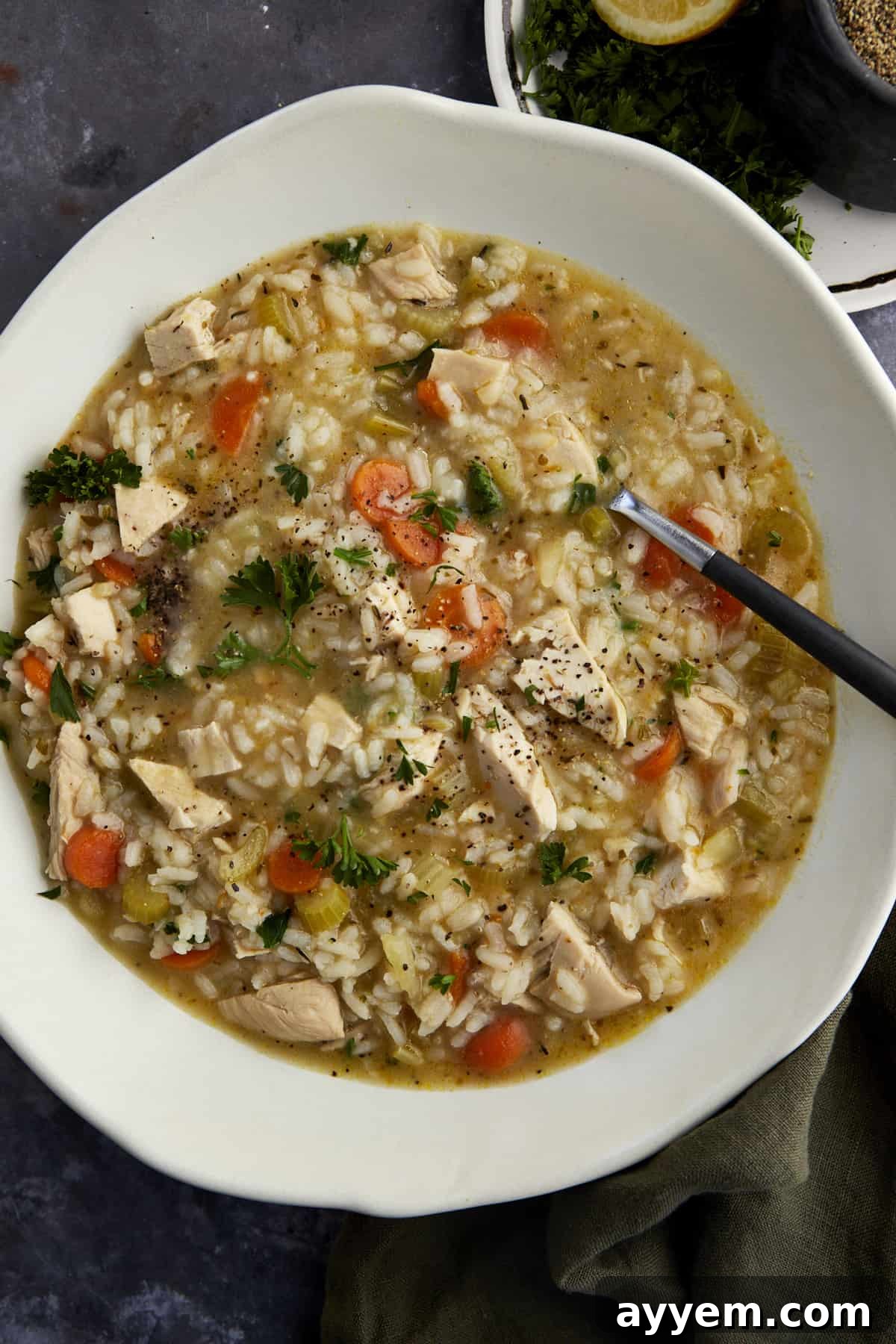 A bowl of creamy chicken and rice soup with a spoon sticking out.