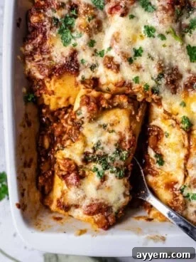 A baked lasagna roll being lifted up with a serving spoon.