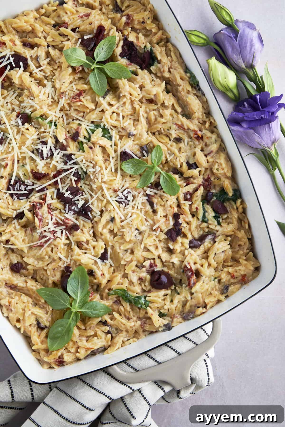 A closer view of the spinach and sun-dried tomato Boursin orzo bake in a baking dish, showing the creamy texture and vibrant ingredients.