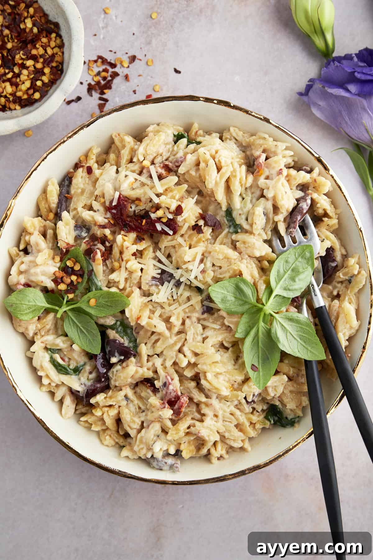 A bowl of spinach and sun-dried tomato boursin orzo bake.
