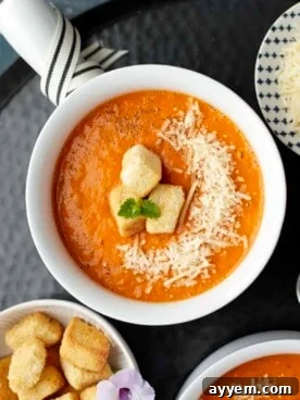 A rustic bowl of rich roasted tomato soup, beautifully topped with golden Parmesan croutons and fresh basil leaves.