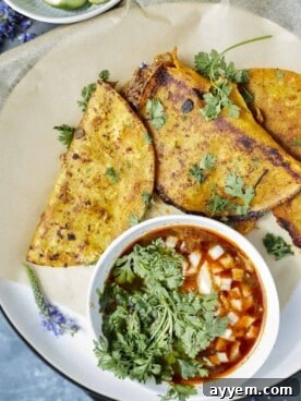 Mouth-watering Slow Cooker Beef Birria tacos arranged on a rustic plate, accompanied by a vibrant bowl of pico de gallo.