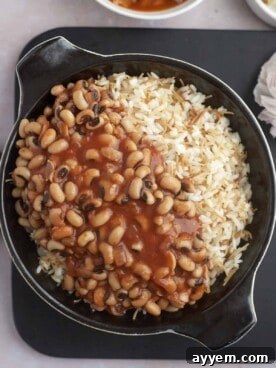 A hearty skillet of vermicelli rice generously topped with a rich black-eyed pea stew, garnished with fresh cilantro.
