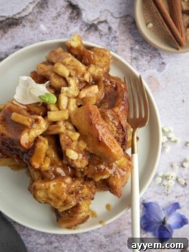 A delightful serving of warm apple caramel cinnamon rolls on a plate, glistening with sweet glaze and caramel drizzle.