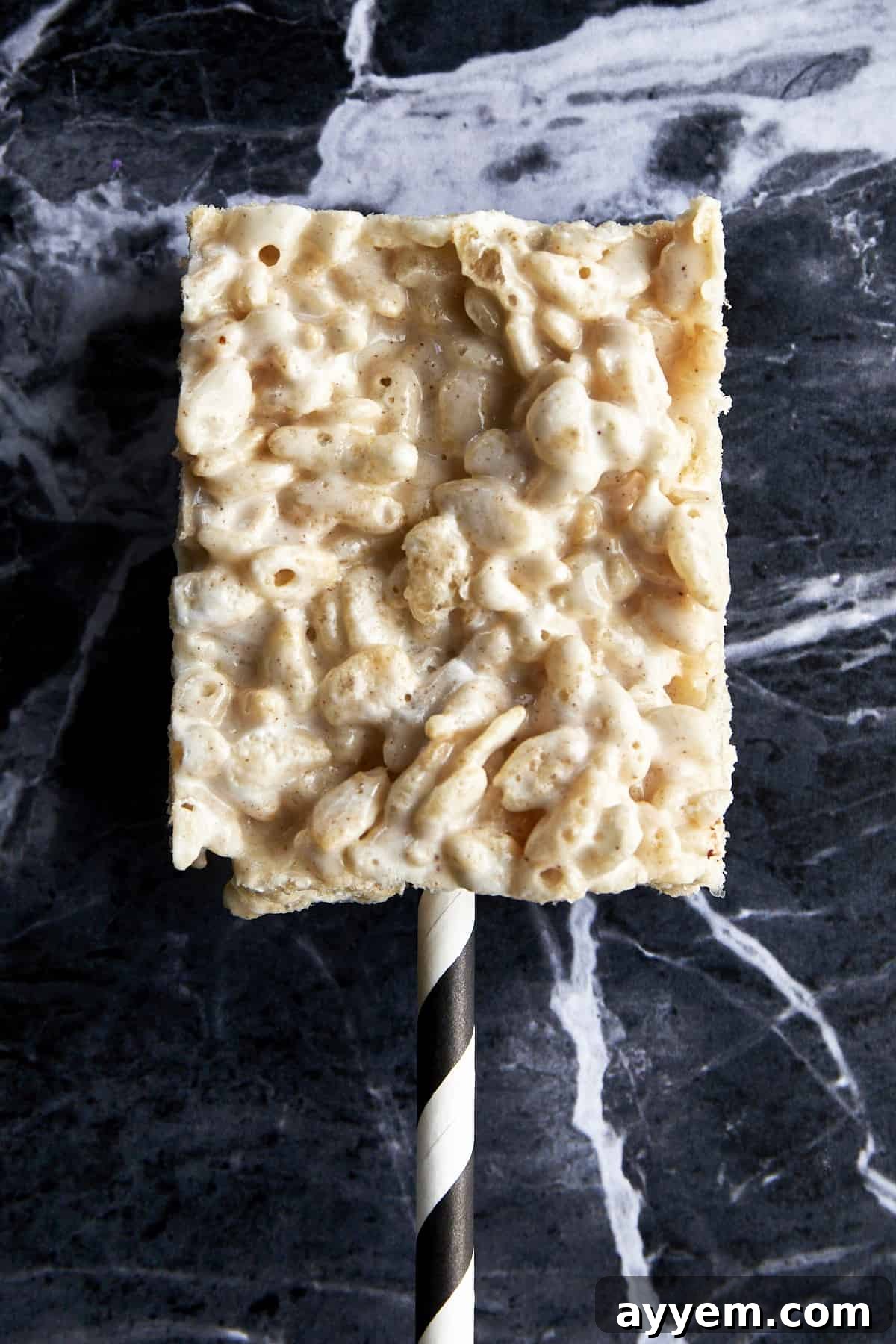 A plain rice krispie treat with a straw sticking out.