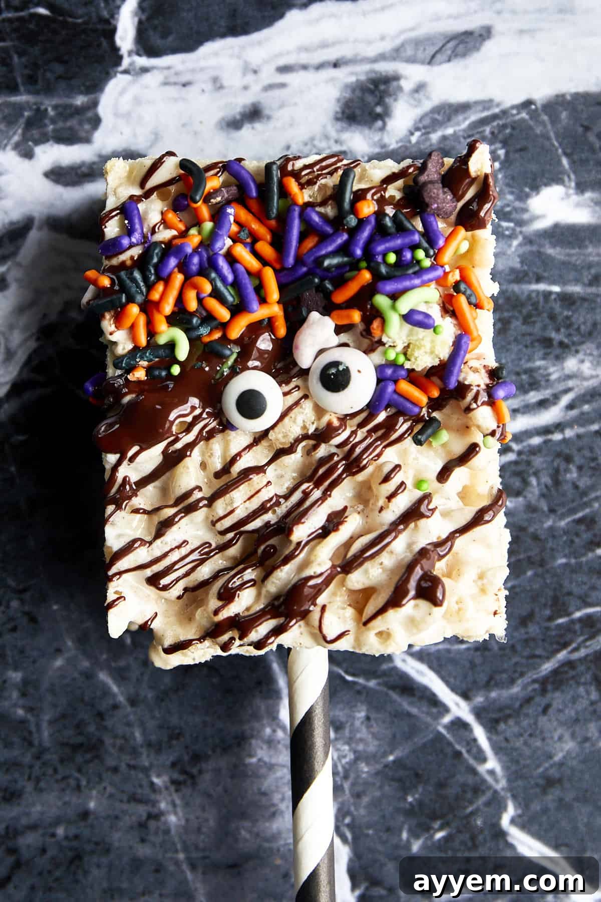 A Halloween rice krispie treat topped with chocolate drizzle, sprinkles, and candy eyes.