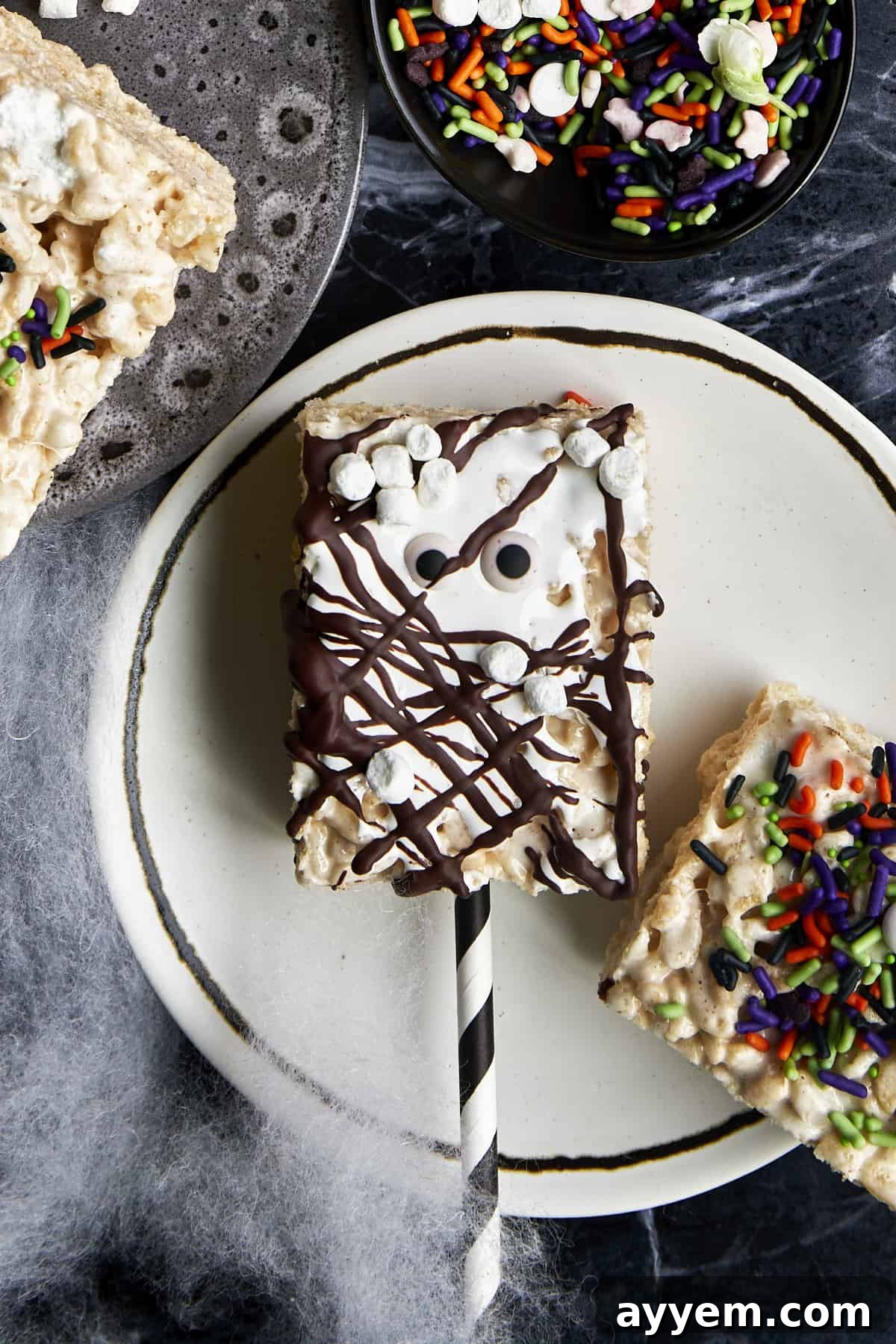 A Halloween rice krispie treat topped with chocolate, marshmallows, and candy eyes.