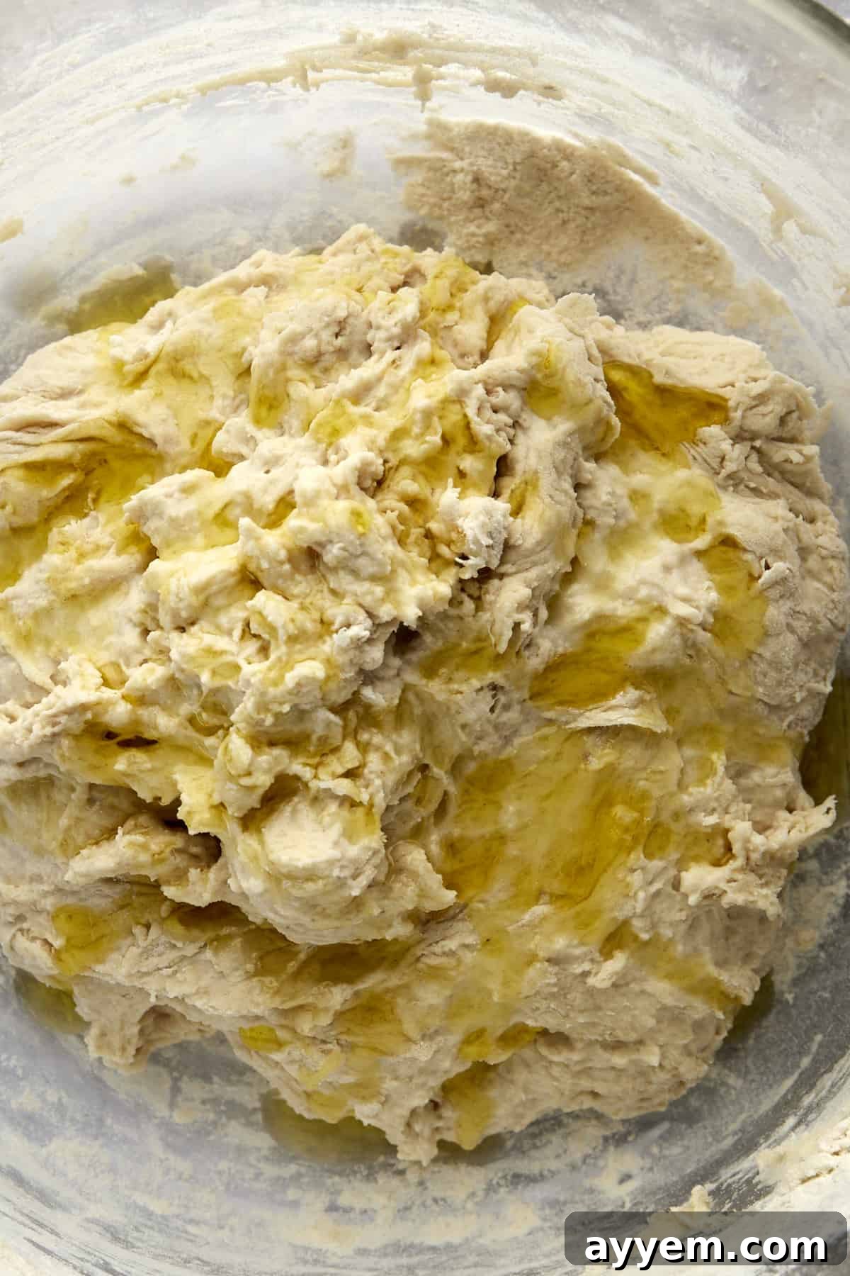 Oil drizzled over bread dough in a bowl.