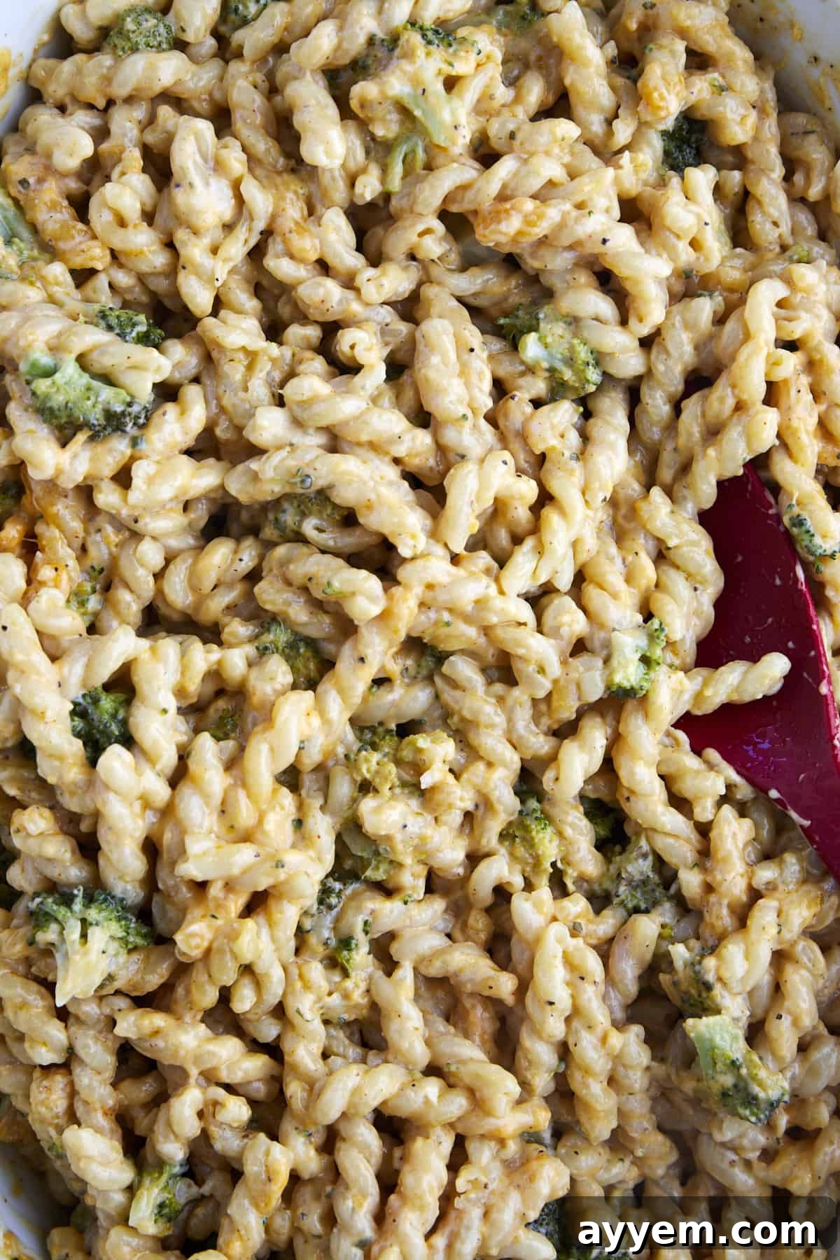 A close-up, appetizing image of baked broccoli mac and cheese in a baking dish, showcasing the creamy, bubbly cheese sauce and tender broccoli florets ready to be enjoyed.