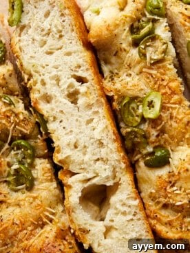 Golden, airy slices of olive focaccia bread, speckled with green olives and a hint of parmesan, drizzled with olive oil.