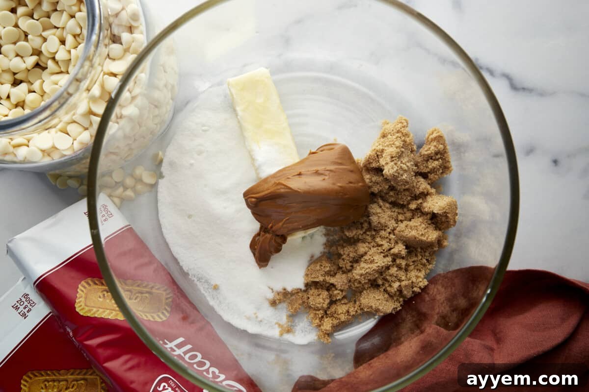 Butter, white sugar, brown sugar, and Biscoff cookie butter in a mixing bowl, ready to be creamed.