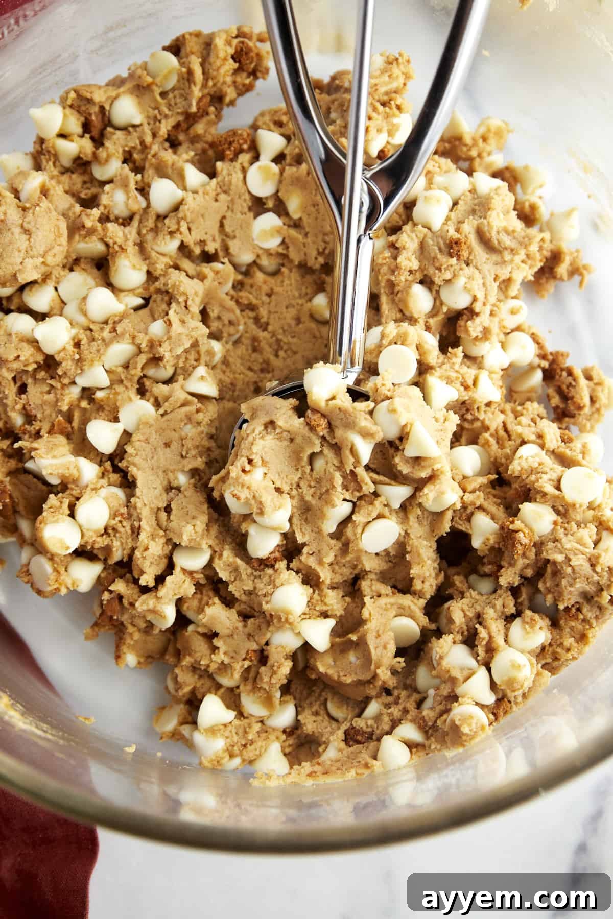 Large scoops of Biscoff cookie dough, ready for baking on a parchment-lined sheet.
